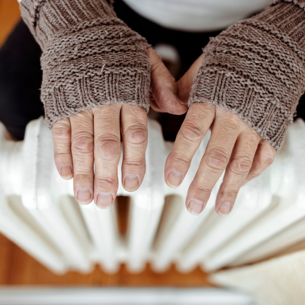 Woman's hands feeling warmth on a radiator. Exploring reasons for constant cold hands.