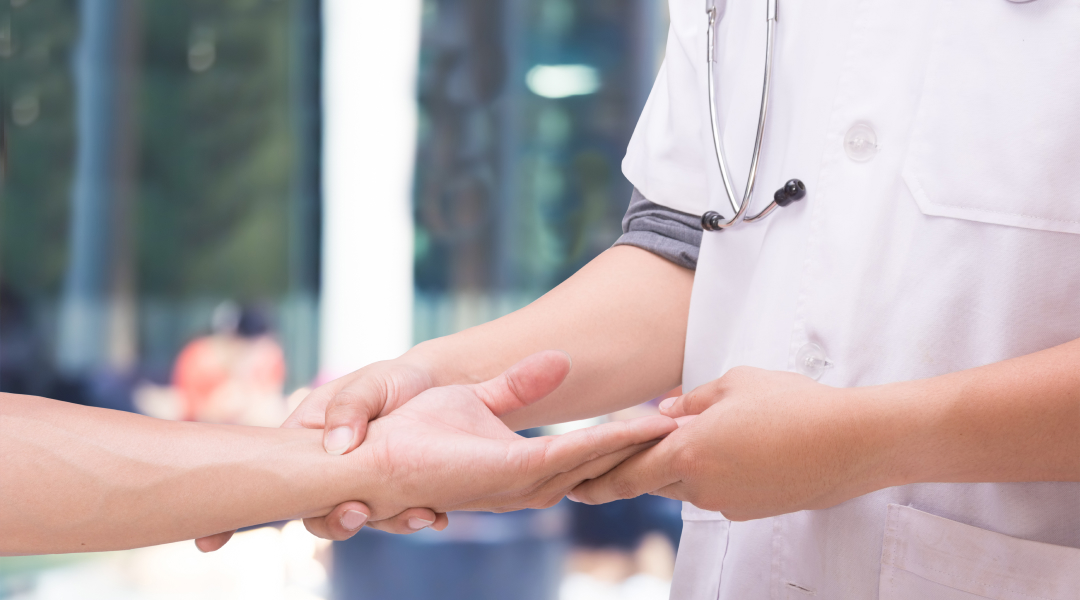 A doctor holding the hand of a patient.