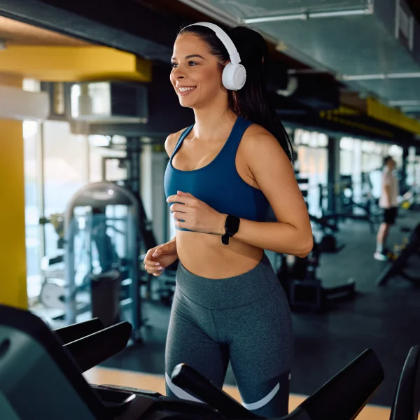 Une femme court sur un tapis roulant dans une salle de sport, soulignant le rôle de l’exercice dans la gestion efficace du stress.