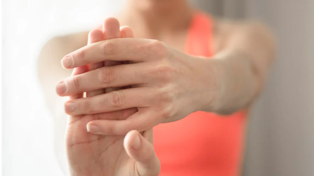 A woman stretches her hands out, one hand appearing numb, as she seeks relief or mobility.