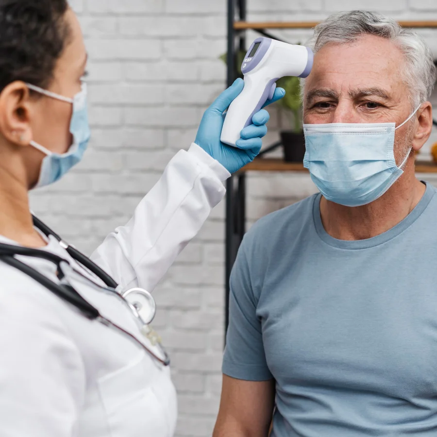 A doctor with a mask examines an older man, noting his cold hands during the consultation.